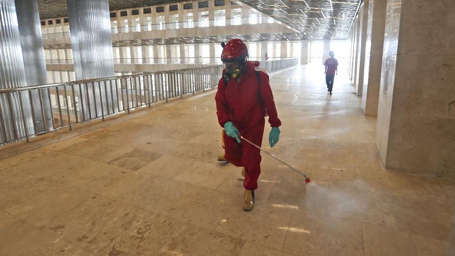 Seorang petugas pemadam kebakaran menyemprotkan desinfektan dalam upaya membantu mengekang penyebaran virus corona baru di Masjid Istiqlal di Jakarta. AP/Achmad Ibrahim