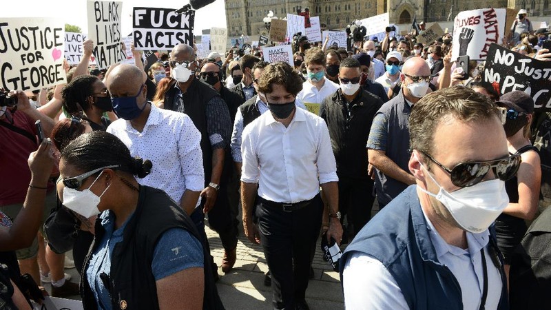 Prime Minister Justin Trudeau shakes hands with a participant who gave him a Black Lives Matter T-shirt as he takes part in an anti-racism protest on Parliament Hill during the coronavirus pandemic in Ottawa, Ontario, Friday, June 5, 2020. The death of George Floyd, a black man who died after he was restrained by Minneapolis police officers on May 25, has ignited protests in the U.S. and worldwide over racial injustice and police brutality. (Sean Kilpatrick/The Canadian Press via AP)