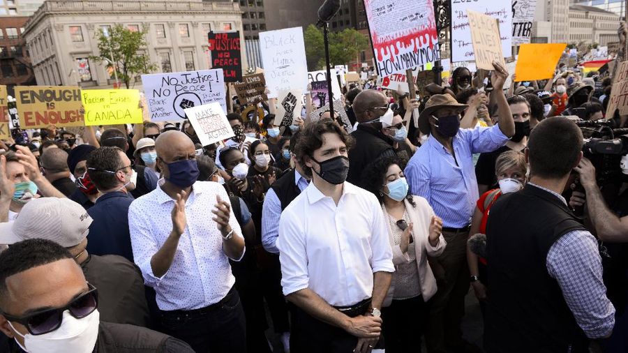 Prime Minister Justin Trudeau shakes hands with a participant who gave him a Black Lives Matter T-shirt as he takes part in an anti-racism protest on Parliament Hill during the coronavirus pandemic in Ottawa, Ontario, Friday, June 5, 2020. The death of George Floyd, a black man who died after he was restrained by Minneapolis police officers on May 25, has ignited protests in the U.S. and worldwide over racial injustice and police brutality. (Sean Kilpatrick/The Canadian Press via AP)