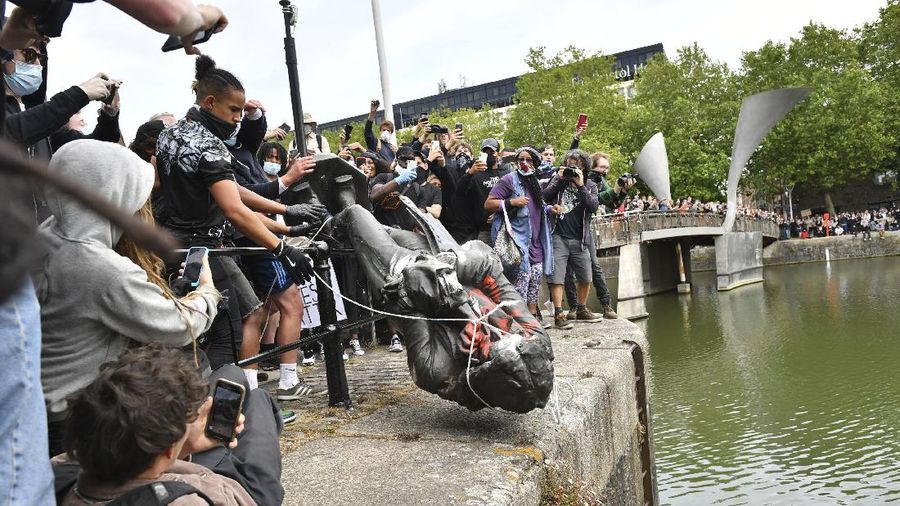 Protesters throw a statue of slave trader Edward Colston into Bristol harbour, during a Black Lives Matter protest rally, in Bristol, England, Sunday June 7, 2020, in response to the recent killing of George Floyd by police officers in Minneapolis, USA, that has led to protests in many countries and across the US. (Ben Birchall/PA via AP)