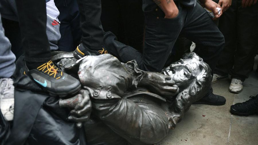 Protesters pull down a statue of slave trader Edward Colston during a Black Lives Matter protest rally on College Green, Bristol, England, Sunday June 7, 2020, in response to the recent killing of George Floyd by police officers in Minneapolis, USA, that has led to protests in many countries and across the US. (Ben Birchall/PA via AP)