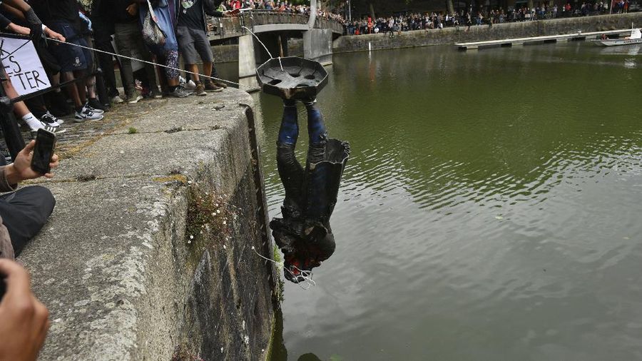 Protesters pull down a statue of slave trader Edward Colston during a Black Lives Matter protest rally on College Green, Bristol, England, Sunday June 7, 2020, in response to the recent killing of George Floyd by police officers in Minneapolis, USA, that has led to protests in many countries and across the US. (Ben Birchall/PA via AP)