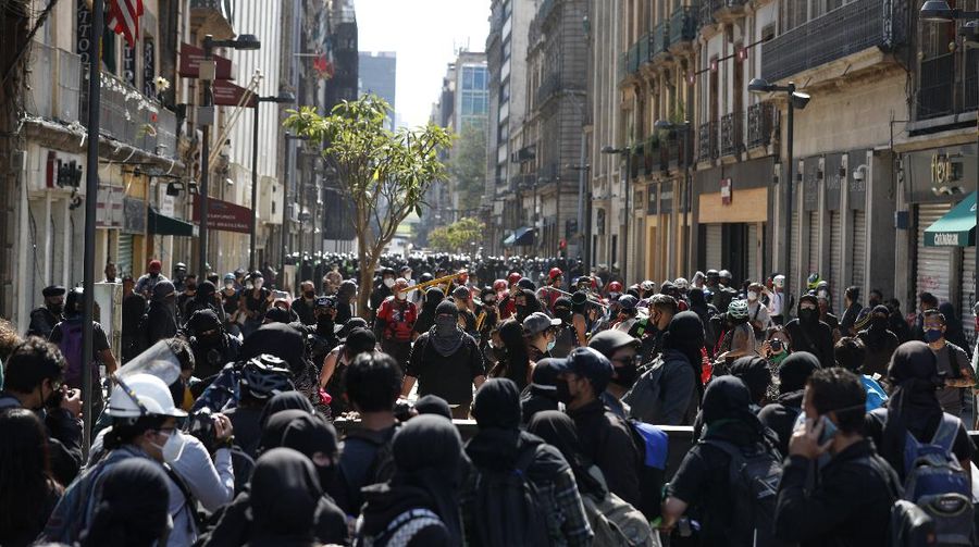 A line of police and anarchist protestors stare at each other from a distance after the demonstrators tore down barriers to enter pedestrian Madero street, which has been closed for months due to the coronavirus pandemic, during a march in Mexico City, Monday, June 8, 2020. (AP Photo/Rebecca Blackwell)