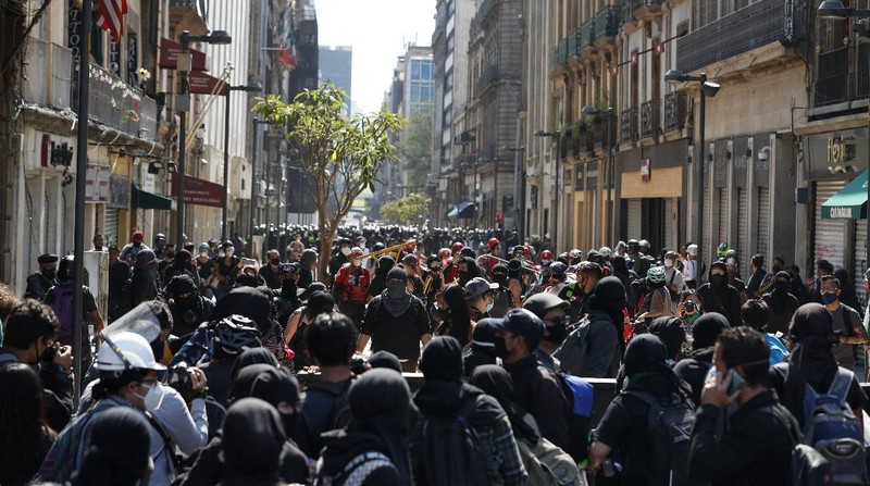 A line of police and anarchist protestors stare at each other from a distance after the demonstrators tore down barriers to enter pedestrian Madero street, which has been closed for months due to the coronavirus pandemic, during a march in Mexico City, Monday, June 8, 2020. (AP Photo/Rebecca Blackwell)