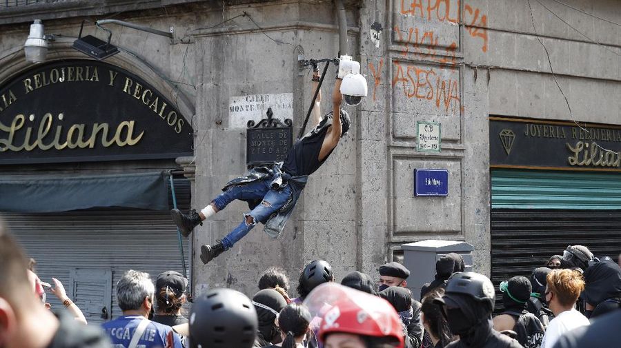 A line of police and anarchist protestors stare at each other from a distance after the demonstrators tore down barriers to enter pedestrian Madero street, which has been closed for months due to the coronavirus pandemic, during a march in Mexico City, Monday, June 8, 2020. (AP Photo/Rebecca Blackwell)