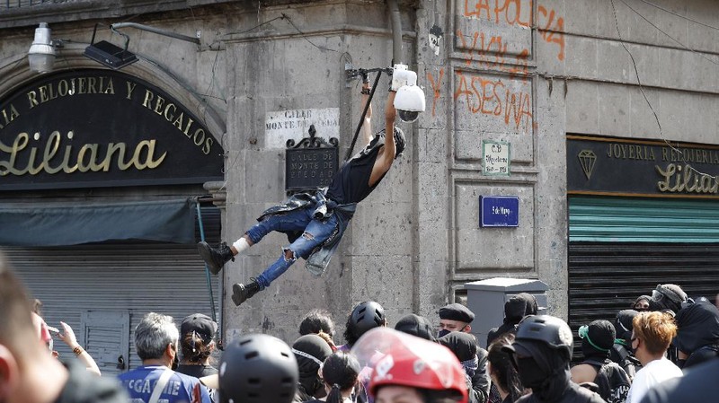 A line of police and anarchist protestors stare at each other from a distance after the demonstrators tore down barriers to enter pedestrian Madero street, which has been closed for months due to the coronavirus pandemic, during a march in Mexico City, Monday, June 8, 2020. (AP Photo/Rebecca Blackwell)