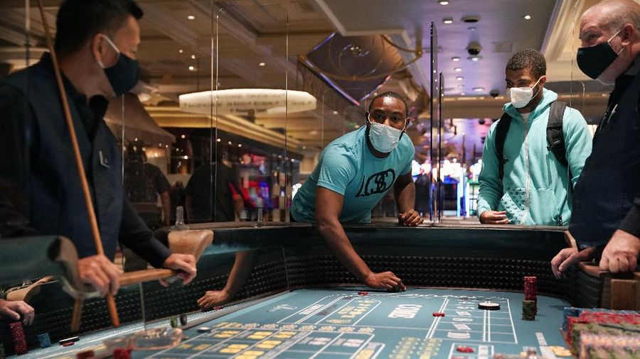 A man plays craps at the reopening of the Bellagio hotel and casino Thursday, June 4, 2020, in Las Vegas. Casinos in Nevada were allowed to reopen on Thursday for the first time after temporary closures as a precaution against the coronavirus. (AP Photo/John Locher)