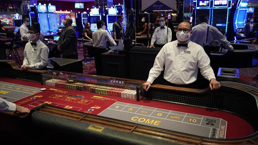 A man plays craps at the reopening of the Bellagio hotel and casino Thursday, June 4, 2020, in Las Vegas. Casinos in Nevada were allowed to reopen on Thursday for the first time after temporary closures as a precaution against the coronavirus. (AP Photo/John Locher)