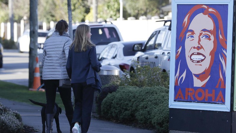 Pedestrians walk past a billboard featuring Prime Minister Jacinda Ardern with the word Aroha, meaning love, in Christchurch, New Zealand, Monday, June 8, 2020. New Zealand appears to have completely eradicated the coronavirus, at least for now, after health officials said Monday the last known infected person had recovered. (AP Photo/Mark Baker)