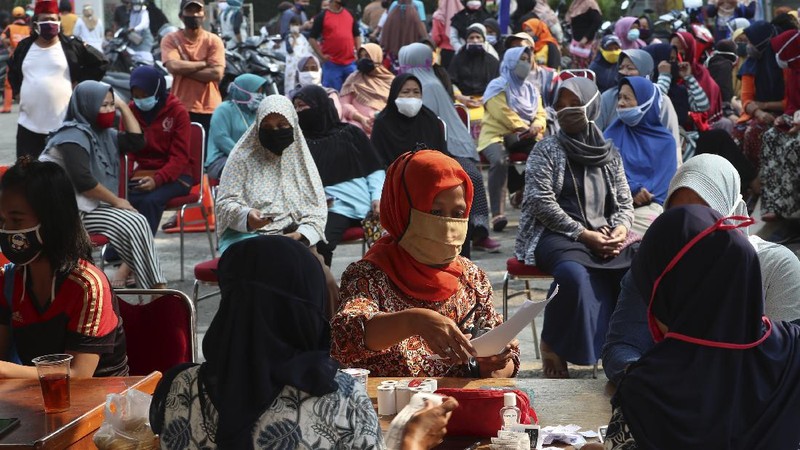 A woman wears a face mask as a precaution against the new coronavirus outbreak as she receives free staple food packages provided by the government for low-income residents in Jakarta, Indonesia, Thursday, June 11, 2020. (AP Photo/Achmad Ibrahim)