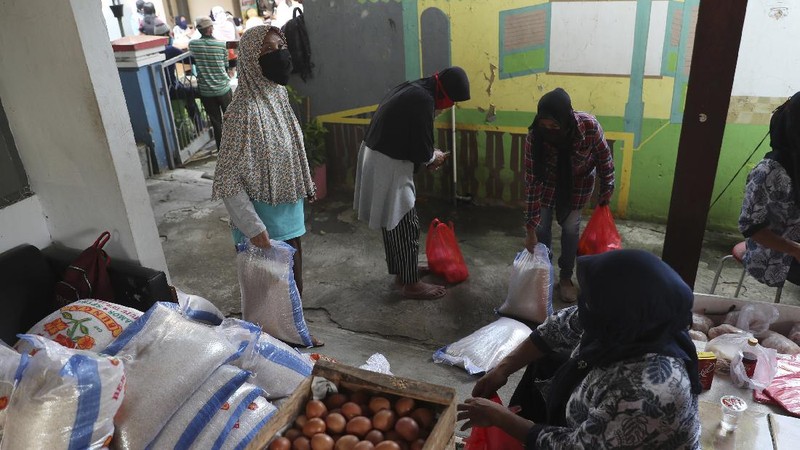 A woman wears a face mask as a precaution against the new coronavirus outbreak as she receives free staple food packages provided by the government for low-income residents in Jakarta, Indonesia, Thursday, June 11, 2020. (AP Photo/Achmad Ibrahim)