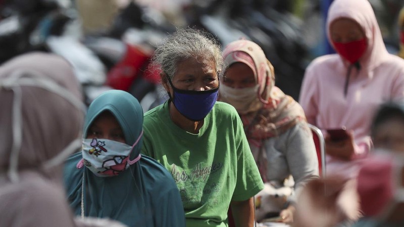 A woman wears a face mask as a precaution against the new coronavirus outbreak as she receives free staple food packages provided by the government for low-income residents in Jakarta, Indonesia, Thursday, June 11, 2020. (AP Photo/Achmad Ibrahim)