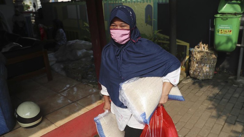 A woman wears a face mask as a precaution against the new coronavirus outbreak as she receives free staple food packages provided by the government for low-income residents in Jakarta, Indonesia, Thursday, June 11, 2020. (AP Photo/Achmad Ibrahim)