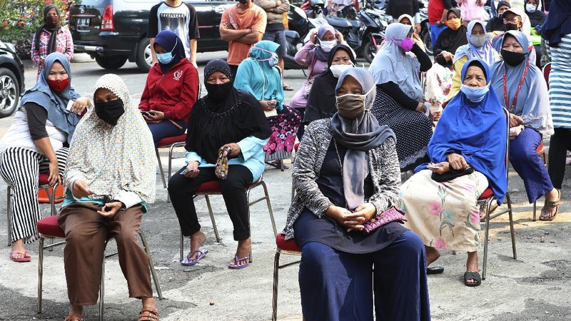 A woman wears a face mask as a precaution against the new coronavirus outbreak as she receives free staple food packages provided by the government for low-income residents in Jakarta, Indonesia, Thursday, June 11, 2020. (AP Photo/Achmad Ibrahim)