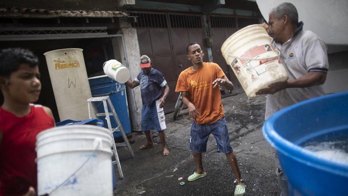 Krisis Air Bersih Venezuela Ditengah Pandemi Residents form a bucket brigade, filling large containers with water provided by a government water truck, in the Petare slum of Caracas, Venezuela, Wednesday, June 10, 2020. Amid water shortages during the COVID-19 pandemic, the government is providing free water to some areas. (AP Photo/Ariana Cubillos)