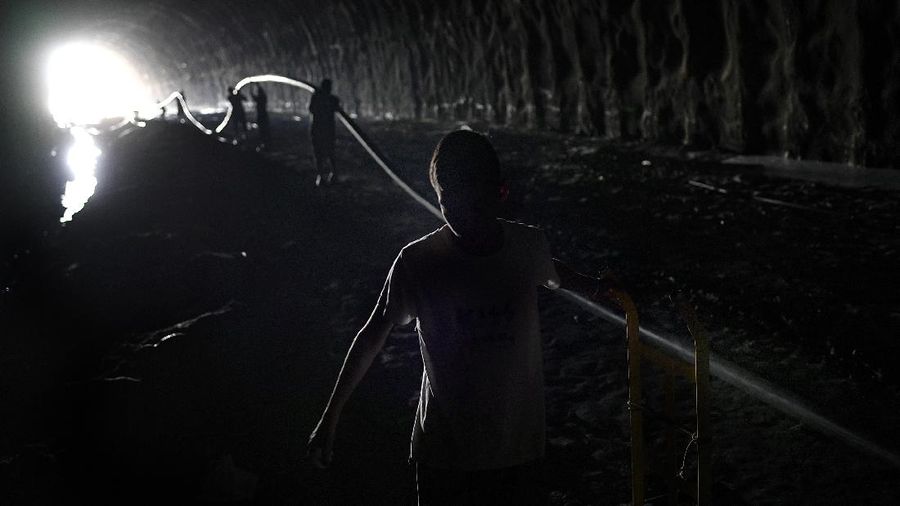 A woman untangles an electrical cord and a hose in order to pump from a large container water provided by a government water truck, in the Petare slum of Caracas, Venezuela, Wednesday, June 10, 2020. Amid water shortages during the COVID-19 pandemic, the government is providing free water to some areas. (AP Photo/Ariana Cubillos)