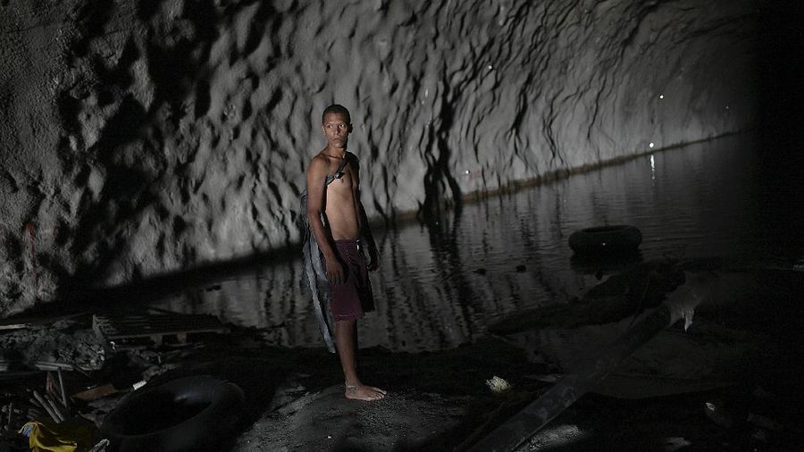A boy helps to carry a water pipe inside an abandoned highway tunnel used as a water catchment in Caracas, Venezuela, Saturday, June 6, 2020. Without potable water from the respective government authorities, residents of the Esperanza neighborhood have organized to create their own water supply collected from inside the never completed Baralt highway tunnel. (AP Photo/Matias Delacroix)