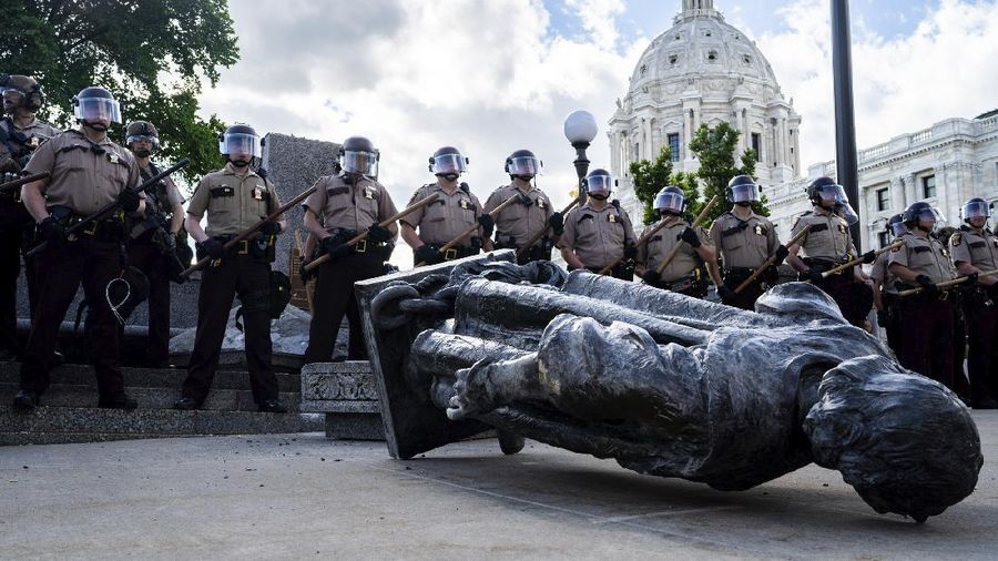 Activists bring down the Christopher Columbus statue in front of the Capitol, Wednesday, June 10, 2020, in St. Paul, Minn. A rope was thrown around the 10-foot bronze statue and it was pulled off its stone pedestal. The protesters included Dakota and Ojibwe Indians who consider Columbus as a symbol of genocide against Native Americans. State Patrol troopers in helmets stood by at a distance but did not try to stop the protesters. (Leila Navidi/Star Tribune via AP)