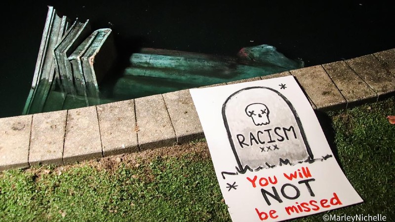 Activists bring down the Christopher Columbus statue in front of the Capitol, Wednesday, June 10, 2020, in St. Paul, Minn. A rope was thrown around the 10-foot bronze statue and it was pulled off its stone pedestal. The protesters included Dakota and Ojibwe Indians who consider Columbus as a symbol of genocide against Native Americans. State Patrol troopers in helmets stood by at a distance but did not try to stop the protesters. (Leila Navidi/Star Tribune via AP)