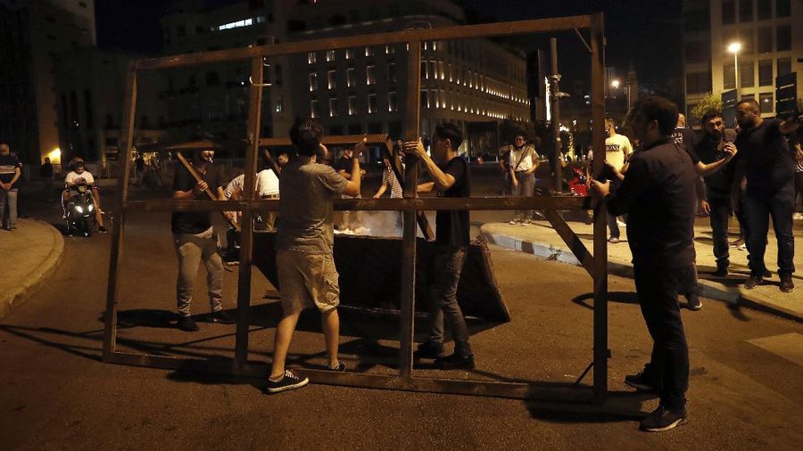 A police officer directs a water cannon to extinguish a shop that was set on fire by protesters during an anti-government protest in Beirut, Lebanon, early Friday, June 12, 2020. Lebanon's prime minister held an emergency Cabinet meeting Friday, hours after demonstrators shut roads across the country with burning tires in renewed nationwide protests spurred by a plunging national currency and economic crisis. (AP Photo/Hussein Malla)