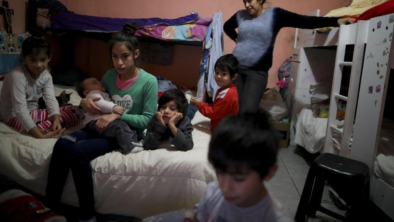 In this June 2, 2020 photo, parish assistant Natividad Benitez serves a hot drink outside a church, during a government-ordered lockdown to curb the spread of the new coronavirus, in the Villa 1-11-14 shanty town of Buenos Aires, Argentina. Since coronavirus came to Argentina, the priest who employs her has gone from serving 350 meals a day to 7000, feeding residents of the poor neighborhood where economic activity has all but stopped due to strict anti-virus measures.  (AP Photo/Natacha Pisarenko)