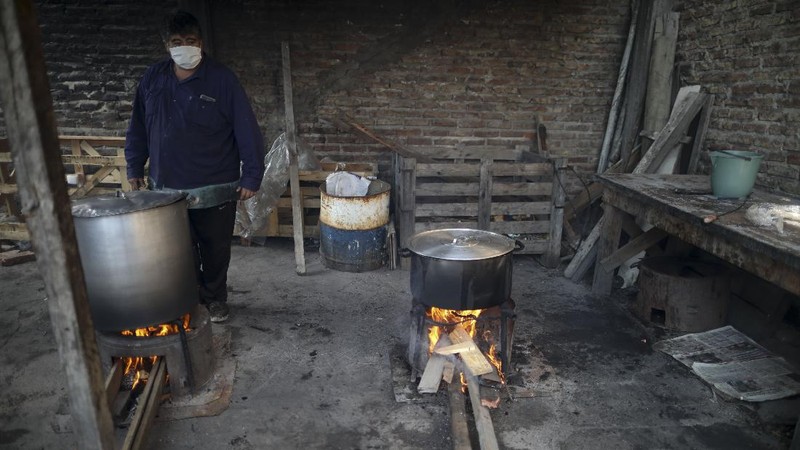 In this June 2, 2020 photo, parish assistant Natividad Benitez serves a hot drink outside a church, during a government-ordered lockdown to curb the spread of the new coronavirus, in the Villa 1-11-14 shanty town of Buenos Aires, Argentina. Since coronavirus came to Argentina, the priest who employs her has gone from serving 350 meals a day to 7000, feeding residents of the poor neighborhood where economic activity has all but stopped due to strict anti-virus measures.  (AP Photo/Natacha Pisarenko)