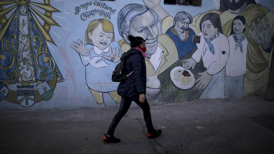 In this June 2, 2020 photo, parish assistant Natividad Benitez serves a hot drink outside a church, during a government-ordered lockdown to curb the spread of the new coronavirus, in the Villa 1-11-14 shanty town of Buenos Aires, Argentina. Since coronavirus came to Argentina, the priest who employs her has gone from serving 350 meals a day to 7000, feeding residents of the poor neighborhood where economic activity has all but stopped due to strict anti-virus measures.  (AP Photo/Natacha Pisarenko)