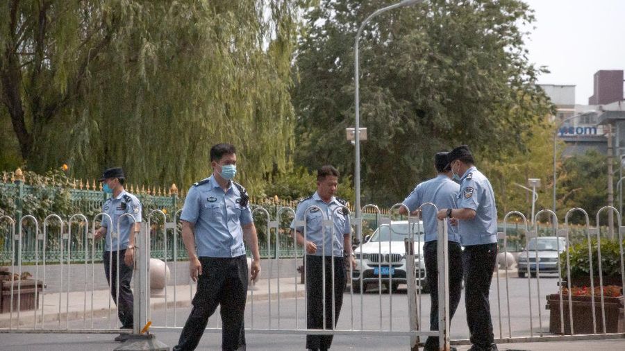 Police officers pull a barricade across a road leading to the a residential neighborhood near the Xinfadi wholesale food market district in Beijing, Saturday, June 13, 2020. Beijing closed the city's largest wholesale food market Saturday after the discovery of seven cases of the new coronavirus in the previous two days. (AP Photo/Mark Schiefelbein)