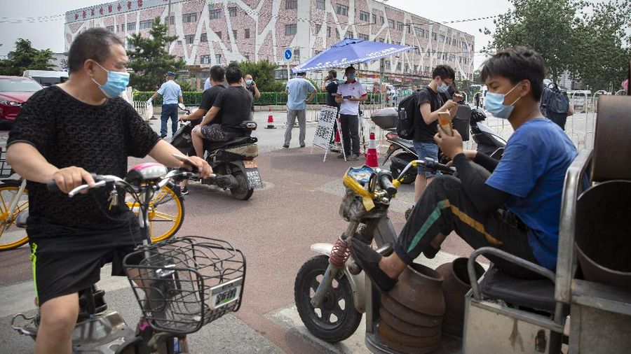 People wearing face masks to protect against the new coronavirus stop at a checkpoint outside the Xinfadi wholesale food market district in Beijing, Saturday, June 13, 2020. Beijing closed the city's largest wholesale food market Saturday after the discovery of seven cases of the new coronavirus in the previous two days. (AP Photo/Mark Schiefelbein)