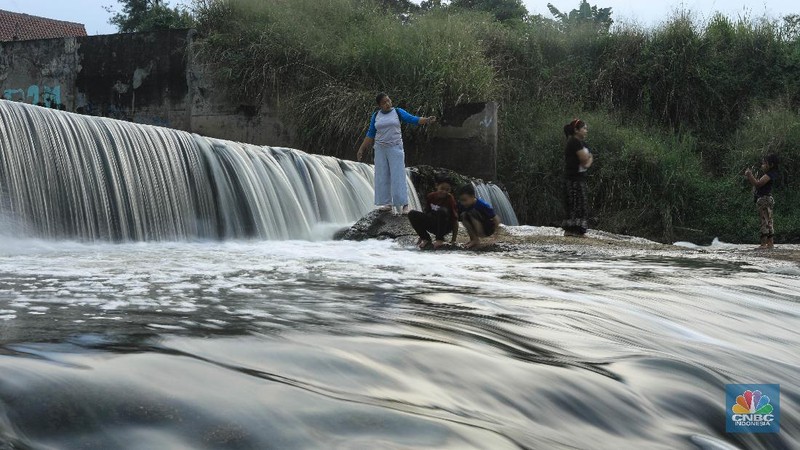 Warga berfoto dengan latar belakang aliran Kali Angke di Situ Lengkong Wetan, Serpong, Tangerang Selatan, Banten, Jumat 12 Juni 2020. Lokasi tersebut menjadi alternatif bagi warga untuk berwisata lokal di tengah masih berlangsungnya penerapan Pembatasan Sosial Berskala Besar (PSBB) di Tangerang Raya untuk menekan penyebaran coronavirus (Covid-19)  (CNBC Indonesia/ Andrean Kristianto)