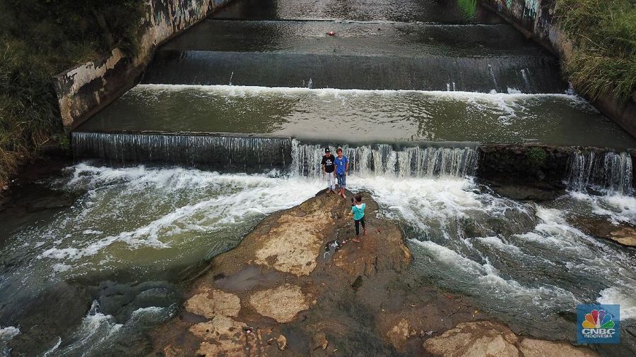 Warga berfoto dengan latar belakang aliran Kali Angke di Situ Lengkong Wetan, Serpong, Tangerang Selatan, Banten, Jumat 12 Juni 2020. Lokasi tersebut menjadi alternatif bagi warga untuk berwisata lokal di tengah masih berlangsungnya penerapan Pembatasan Sosial Berskala Besar (PSBB) di Tangerang Raya untuk menekan penyebaran coronavirus (Covid-19)  (CNBC Indonesia/ Andrean Kristianto)