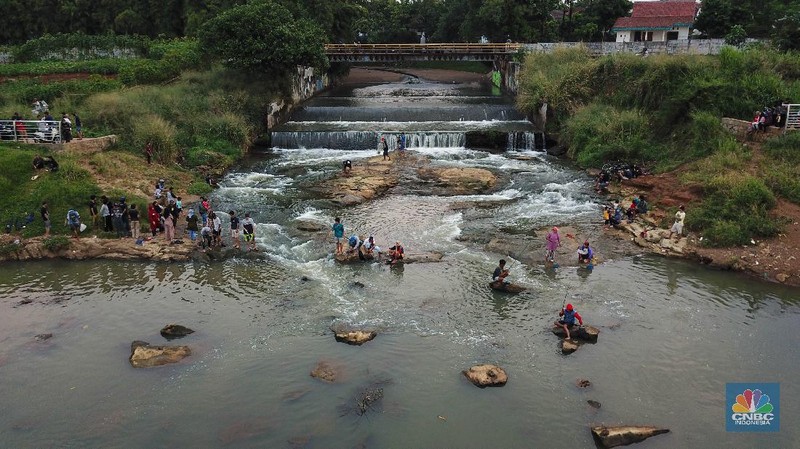 Warga berfoto dengan latar belakang aliran Kali Angke di Situ Lengkong Wetan, Serpong, Tangerang Selatan, Banten, Jumat 12 Juni 2020. Lokasi tersebut menjadi alternatif bagi warga untuk berwisata lokal di tengah masih berlangsungnya penerapan Pembatasan Sosial Berskala Besar (PSBB) di Tangerang Raya untuk menekan penyebaran coronavirus (Covid-19)  (CNBC Indonesia/ Andrean Kristianto)