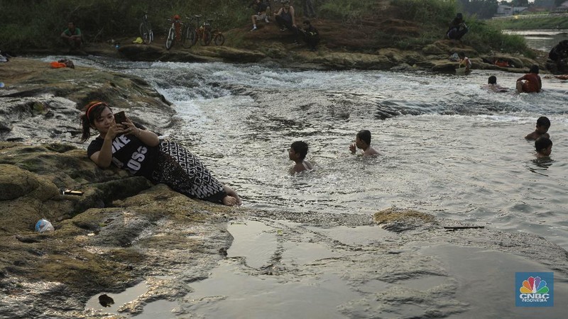 Warga berfoto dengan latar belakang aliran Kali Angke di Situ Lengkong Wetan, Serpong, Tangerang Selatan, Banten, Jumat 12 Juni 2020. Lokasi tersebut menjadi alternatif bagi warga untuk berwisata lokal di tengah masih berlangsungnya penerapan Pembatasan Sosial Berskala Besar (PSBB) di Tangerang Raya untuk menekan penyebaran coronavirus (Covid-19)  (CNBC Indonesia/ Andrean Kristianto)