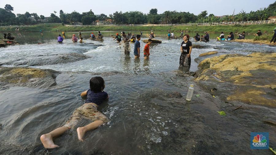 Warga berfoto dengan latar belakang aliran Kali Angke di Situ Lengkong Wetan, Serpong, Tangerang Selatan, Banten, Jumat 12 Juni 2020. Lokasi tersebut menjadi alternatif bagi warga untuk berwisata lokal di tengah masih berlangsungnya penerapan Pembatasan Sosial Berskala Besar (PSBB) di Tangerang Raya untuk menekan penyebaran coronavirus (Covid-19)  (CNBC Indonesia/ Andrean Kristianto)