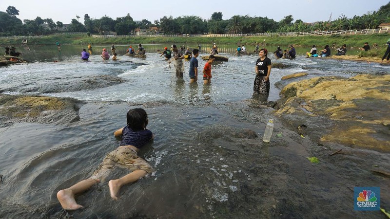 Warga berfoto dengan latar belakang aliran Kali Angke di Situ Lengkong Wetan, Serpong, Tangerang Selatan, Banten, Jumat 12 Juni 2020. Lokasi tersebut menjadi alternatif bagi warga untuk berwisata lokal di tengah masih berlangsungnya penerapan Pembatasan Sosial Berskala Besar (PSBB) di Tangerang Raya untuk menekan penyebaran coronavirus (Covid-19)  (CNBC Indonesia/ Andrean Kristianto)