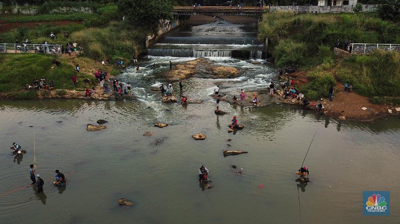 Warga berfoto dengan latar belakang aliran Kali Angke di Situ Lengkong Wetan, Serpong, Tangerang Selatan, Banten, Jumat 12 Juni 2020. Lokasi tersebut menjadi alternatif bagi warga untuk berwisata lokal di tengah masih berlangsungnya penerapan Pembatasan Sosial Berskala Besar (PSBB) di Tangerang Raya untuk menekan penyebaran coronavirus (Covid-19)  (CNBC Indonesia/ Andrean Kristianto)