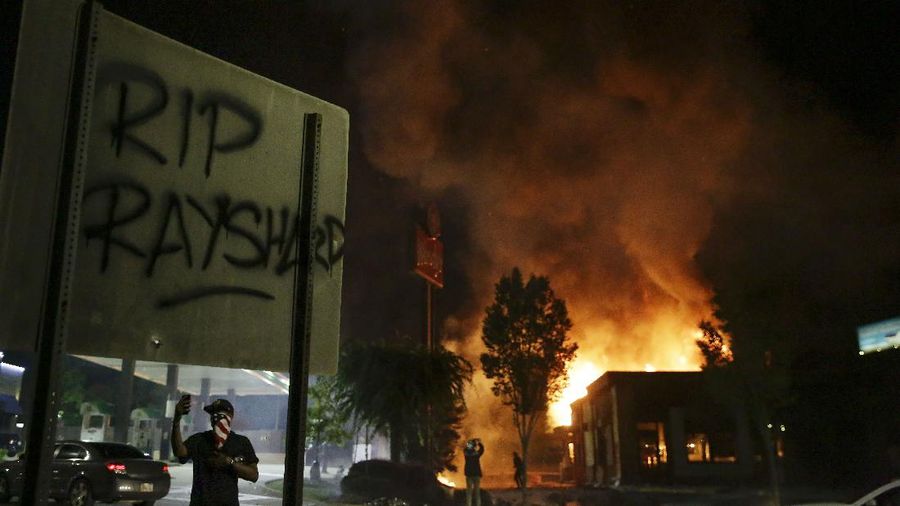 A person is covered with liquid after being officials deployed teargas at protesters Saturday, June 13, 2020, near the Atlanta Wendy's where Rayshard Brooks was shot and killed by police Friday evening following a struggle in the restaurant's drive-thru line in Atlanta. (AP Photo/Brynn Anderson)