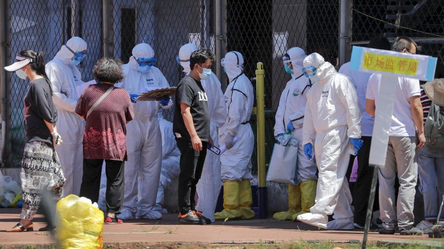 Workers put on protective suits as they wait for people living surrounding the Xinfadi wholesale market arrive to get a nucleic acid test at a stadium in Beijing, Sunday, June 14, 2020. China is reporting its highest daily total of coronavirus cases in two months after the capital's biggest wholesale food market was shut down following a resurgence in local infections. (AP Photo/Andy Wong)