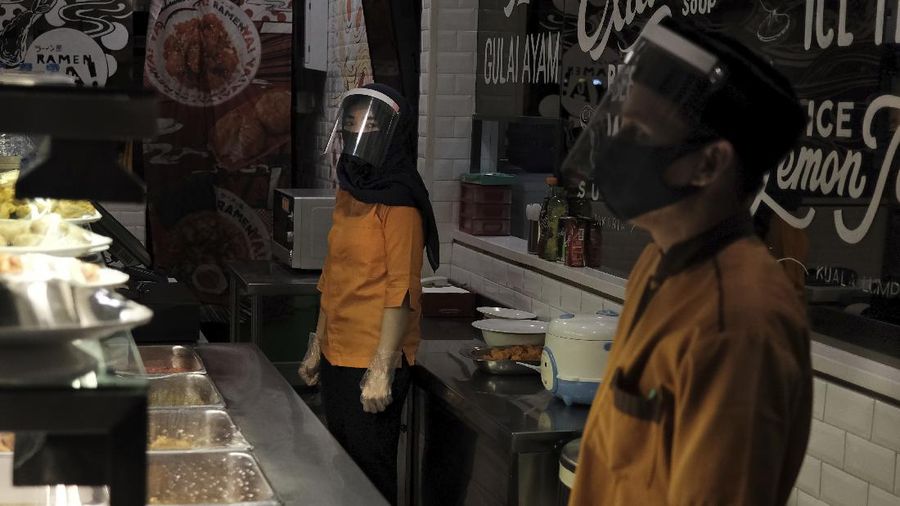 Staff wear face shields as a precaution against the new coronavirus at the reception desk of Senayan City shopping mall in Jakarta, Indonesia, Tuesday, June 9, 2020. As Indonesia's overall virus caseload continues to rise, the capital city has moved to restore normalcy by lifting some restrictions this week, saying that the spread of the virus in the city of 11 million has slowed after peaking in mid-April. (AP Photo/Dita Alangkara)