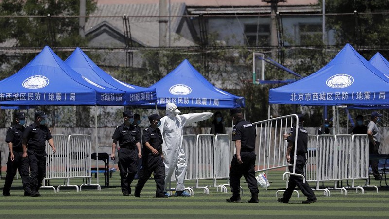 Workers in protective suits direct people who was either living surrounding the Xinfadi wholesale market or have visited to the market to get a nucleic acid test at a stadium in Beijing, Sunday, June 14, 2020. China is reporting its highest daily total of coronavirus cases in two months after the capital's biggest wholesale food market was shut down following a resurgence in local infections. (AP Photo/Andy Wong)