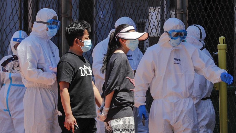 Workers in protective suits direct people who was either living surrounding the Xinfadi wholesale market or have visited to the market to get a nucleic acid test at a stadium in Beijing, Sunday, June 14, 2020. China is reporting its highest daily total of coronavirus cases in two months after the capital's biggest wholesale food market was shut down following a resurgence in local infections. (AP Photo/Andy Wong)