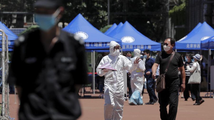 Workers put on protective suits as they wait for people living surrounding the Xinfadi wholesale market arrive to get a nucleic acid test at a stadium in Beijing, Sunday, June 14, 2020. China is reporting its highest daily total of coronavirus cases in two months after the capital's biggest wholesale food market was shut down following a resurgence in local infections. (AP Photo/Andy Wong)
