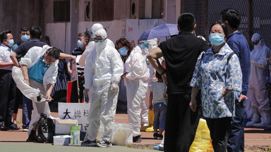 Workers in protective suits direct people who was either living surrounding the Xinfadi wholesale market or have visited to the market to get a nucleic acid test at a stadium in Beijing, Sunday, June 14, 2020. China is reporting its highest daily total of coronavirus cases in two months after the capital's biggest wholesale food market was shut down following a resurgence in local infections. (AP Photo/Andy Wong)