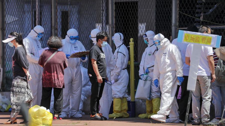 Workers in protective suits direct people who was either living surrounding the Xinfadi wholesale market or have visited to the market to get a nucleic acid test at a stadium in Beijing, Sunday, June 14, 2020. China is reporting its highest daily total of coronavirus cases in two months after the capital's biggest wholesale food market was shut down following a resurgence in local infections. (AP Photo/Andy Wong)