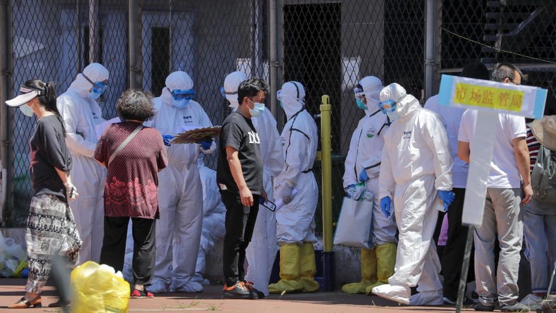 Workers in protective suits direct people who was either living surrounding the Xinfadi wholesale market or have visited to the market to get a nucleic acid test at a stadium in Beijing, Sunday, June 14, 2020. China is reporting its highest daily total of coronavirus cases in two months after the capital's biggest wholesale food market was shut down following a resurgence in local infections. (AP Photo/Andy Wong)
