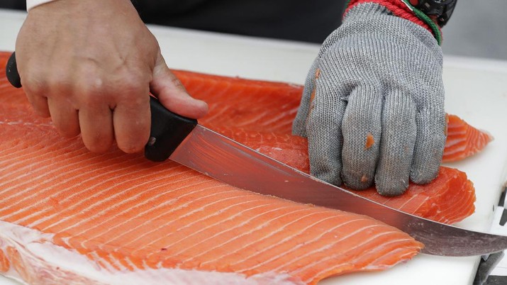 Jim Lagucik, of Trident Seafoods, cuts a Copper River King Salmon Friday, May 18, 2018, at Seattle-Tacoma International Airport in Seattle. The fish was on a plane carrying thousands of pounds of the first shipment of Copper River salmon and the annual arrival of the fish is a rite of spring in Seattle where the fish are prized for their flavor and bring the highest prices at restaurants and fish markets. (AP Photo/Ted S. Warren)