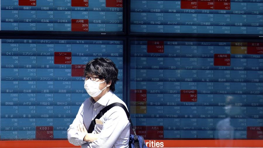 A man walks in front of an electronic stock board showing Japan's Nikkei 225 index at a securities firm in Tokyo Wednesday, June 17, 2020. Major Asian stock markets declined Wednesday after Wall Street gained on hopes for a global economic recovery and Japan's exports sank. (AP Photo/Eugene Hoshiko)