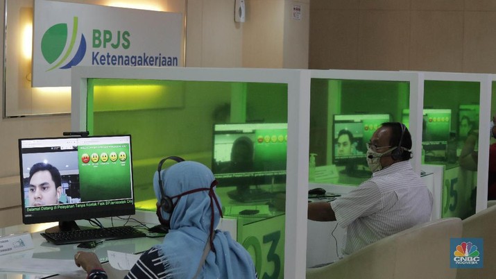 Layanan BPJS Ketenagakerjaan (CNBC Indonesia/ Muhammad Sabki) Peserta BP Jamsostek konsultasi layanan tanpa kontak fisik dengan virtual di Kantor Cabang BPJS Ketenagakerjaan Cilandak, Kamis (18/6/2020). Layanan secara virtual ini merupakan penerapan sesuai dengan protokol kesehatan tanpa harus kontak langsung antara petugas dan peserta BP Jamsostek dalam rangka mencegah penularan COVID-19. Kepala Kantor Cabang Puspitaningsih mengatakan adanya layanan konsultasi tanpa kontak fisik ini di Cabang Cilandak ini disesuaikan dengan aturan protokol kesehatan dan untuk memutus penyebaran Covid-19. Kantor cabang ini menyediakan skat-skat yang dilengkapi layar monitor yang terhubung dengan petugas secara video conference untuk kebutuhan komunikasi dan verifikasi data.