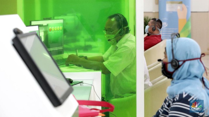 Layanan BPJS Ketenagakerjaan (CNBC Indonesia/ Muhammad Sabki) Peserta BP Jamsostek konsultasi layanan tanpa kontak fisik dengan virtual di Kantor Cabang BPJS Ketenagakerjaan Cilandak, Kamis (18/6/2020). Layanan secara virtual ini merupakan penerapan sesuai dengan protokol kesehatan tanpa harus kontak langsung antara petugas dan peserta BP Jamsostek dalam rangka mencegah penularan COVID-19. Kepala Kantor Cabang Puspitaningsih mengatakan adanya layanan konsultasi tanpa kontak fisik ini di Cabang Cilandak ini disesuaikan dengan aturan protokol kesehatan dan untuk memutus penyebaran Covid-19. Kantor cabang ini menyediakan skat-skat yang dilengkapi layar monitor yang terhubung dengan petugas secara video conference untuk kebutuhan komunikasi dan verifikasi data.
