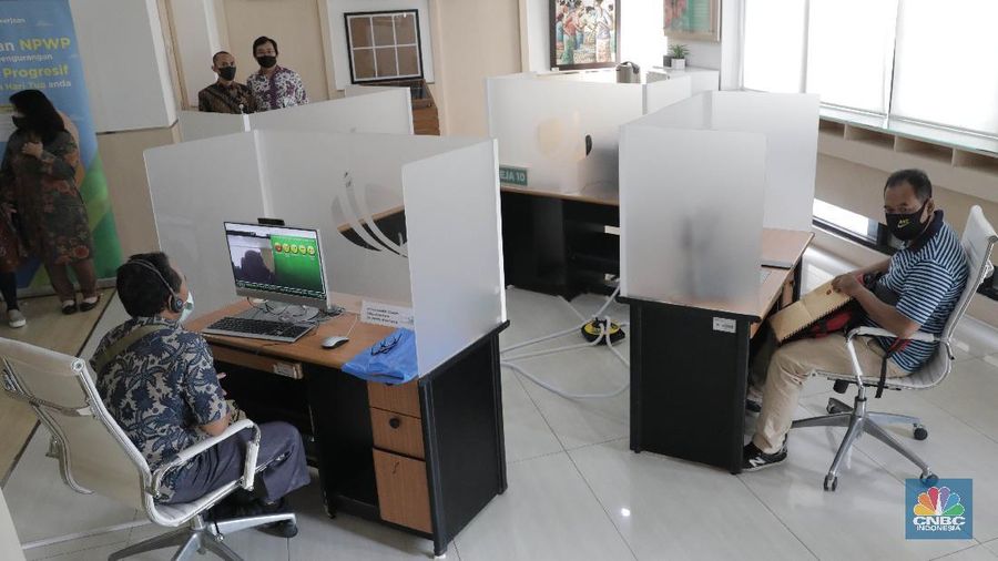 Peserta BP Jamsostek konsultasi layanan tanpa kontak fisik dengan virtual di Kantor Cabang BPJS Ketenagakerjaan Cilandak, Kamis (18/6/2020). Layanan secara virtual ini merupakan penerapan sesuai dengan protokol kesehatan tanpa harus kontak langsung antara petugas dan peserta BP Jamsostek dalam rangka mencegah penularan COVID-19. Kepala Kantor Cabang Puspitaningsih mengatakan adanya layanan konsultasi tanpa kontak fisik ini di Cabang Cilandak ini disesuaikan dengan aturan protokol kesehatan dan untuk memutus penyebaran Covid-19.  Kantor cabang ini menyediakan skat-skat yang dilengkapi layar monitor yang terhubung dengan petugas secara video conference untuk kebutuhan komunikasi dan verifikasi data. 